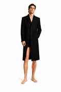 Male model wearing LONG COMMAND COAT 000 with very short black lycra shorts and bare feet — front view